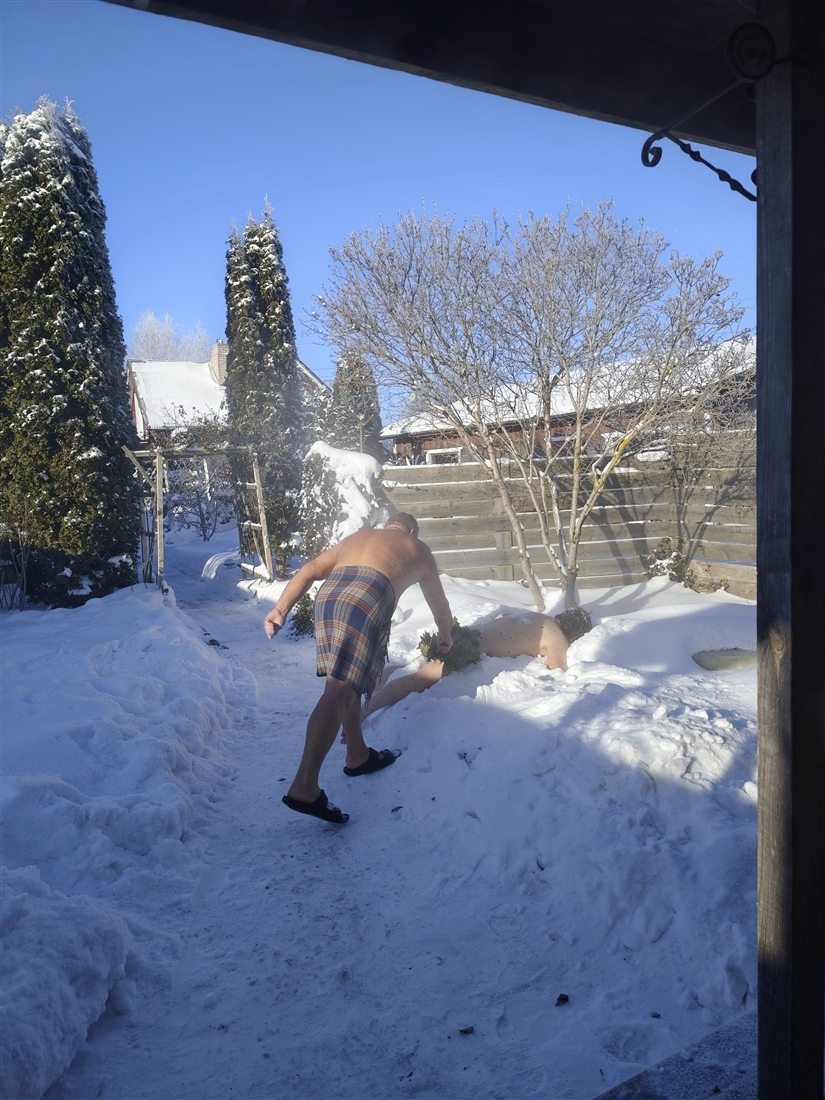 サウナの合間に、庭の雪で体を冷やす様子