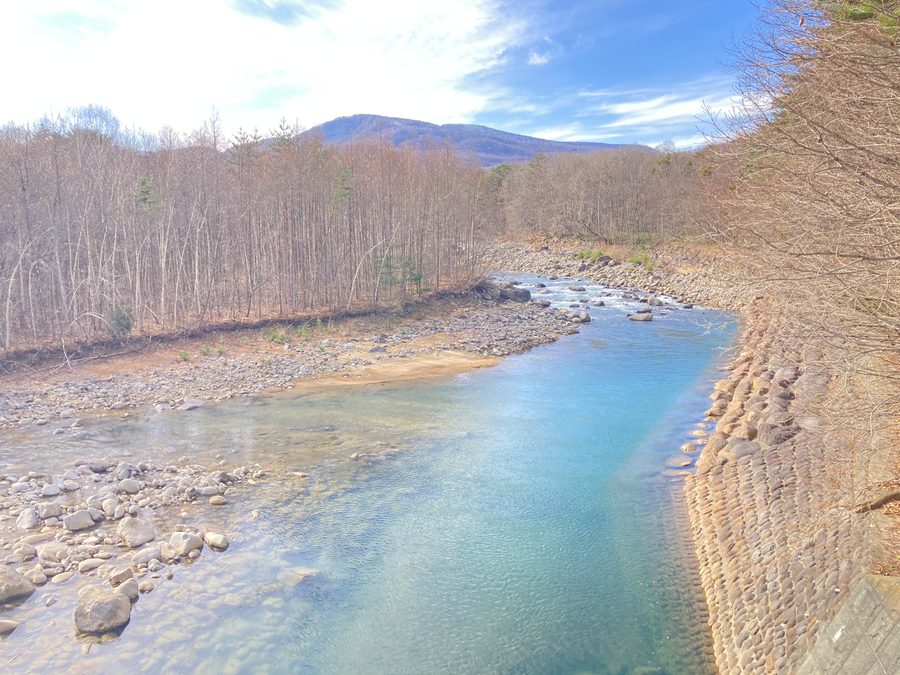 薪土場の近くを流れる、青く澄んだ川と冬枯れの森