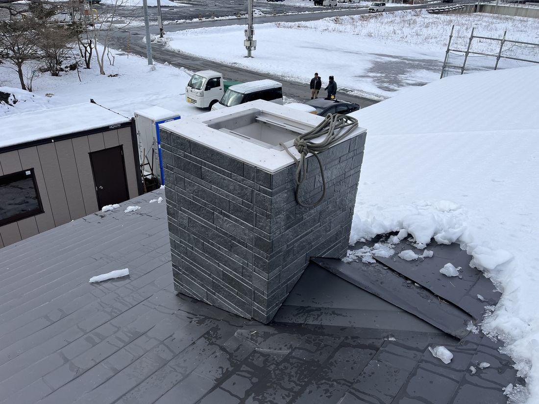 雪の屋根の上での煙突囲いの工事