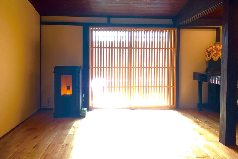 和室に置かれたウォームアーツのペレットストーブと、障子ごしの光